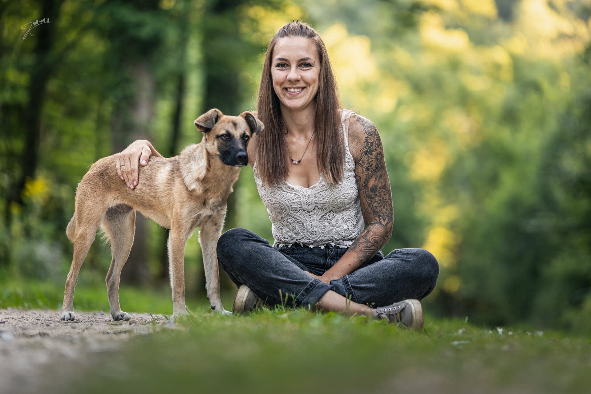 Nicole Sütterlin sitzt mit ihrer Hündin Mira auf einem Waldweg im goldenen Abendlicht